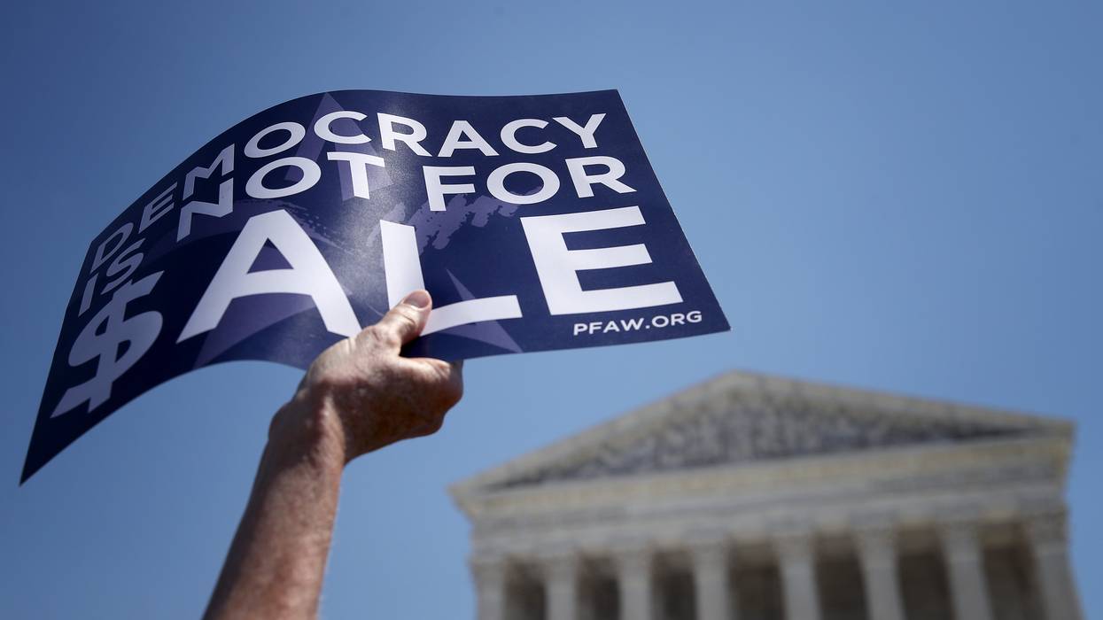 A person holds a sign reading, "Democracy is not for sale."
