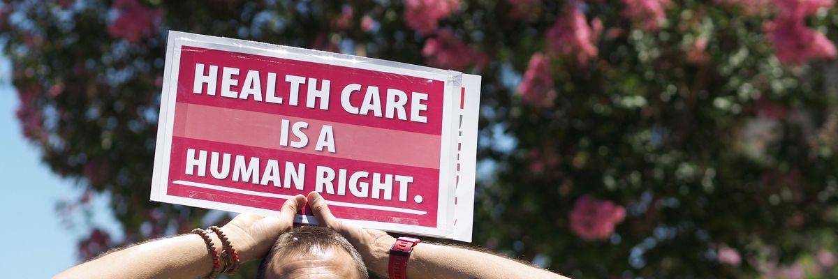 A person holds a sign reading, "Healthcare is a human right."