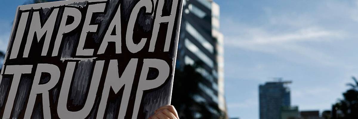 A person holds a sign reading "Impeach Trump" as protestors march