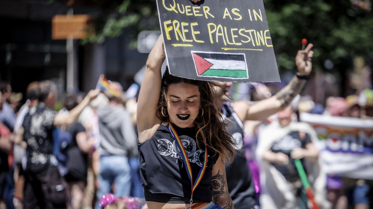 A person holds a sign reading "Queer as in Free Palestine" at a Pride Parade.