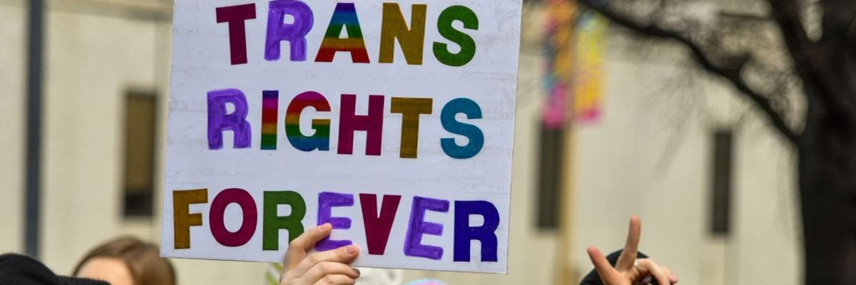 A person holds a sign reading, "Trans rights forever."