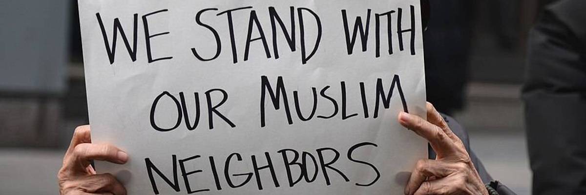 A person holds a sign reading, "We stand with our Muslim neighbors."