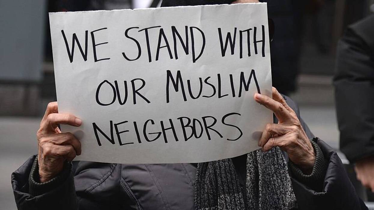 A person holds a sign reading, "We stand with our Muslim neighbors."