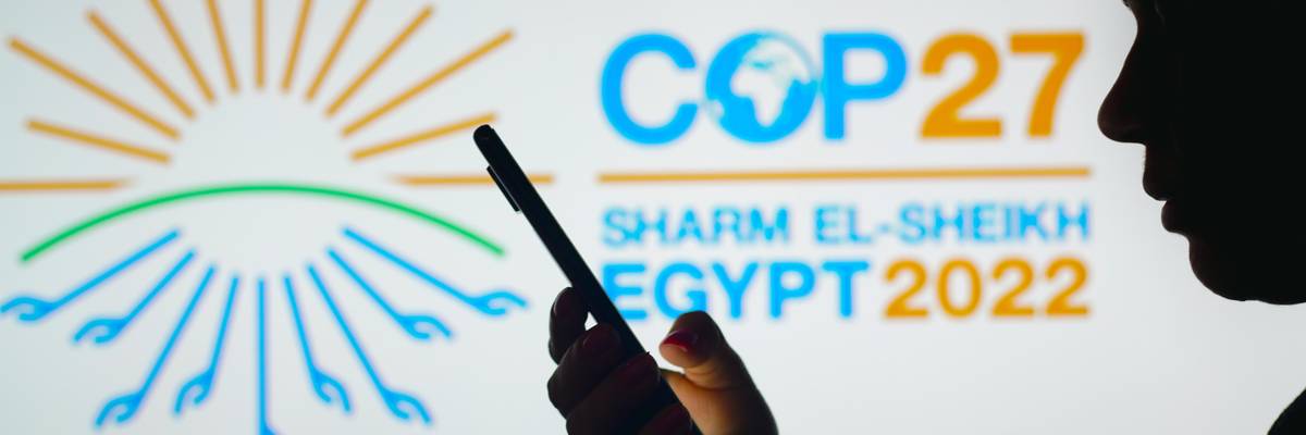 A person holds a smartphone with the United Nations COP27 logo in the background.
