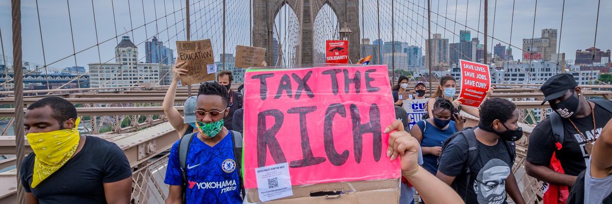 A person holds a Tax The Rich sign at a June 27, 2020 protest march on the Brooklyn Bridge in New York City.