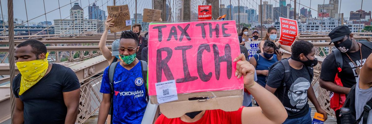A person holds a Tax The Rich sign at a June 27, 2020 protest march on the Brooklyn Bridge in New York City.