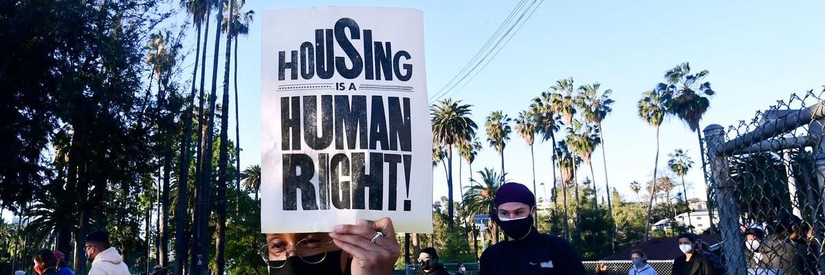 A person holds up a flyer saying, "Housing is a human right."