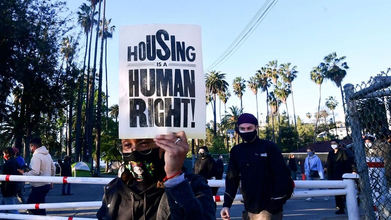 A person holds up a flyer saying, "Housing is a human right."