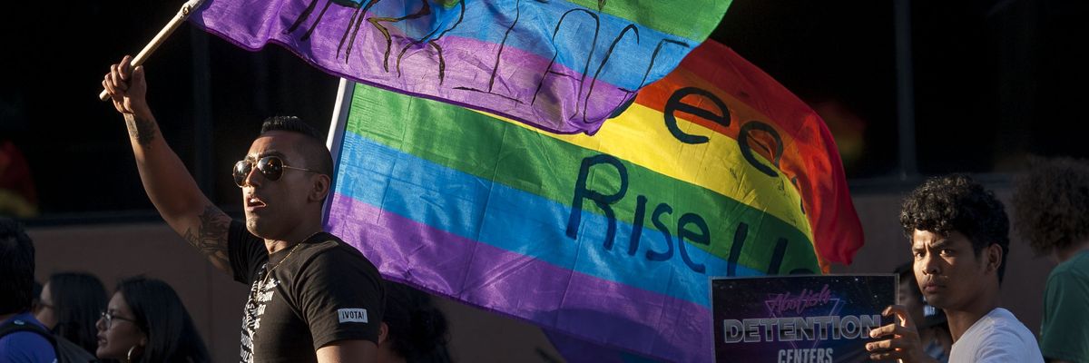 A person in a black shirt waves a Pride flag.