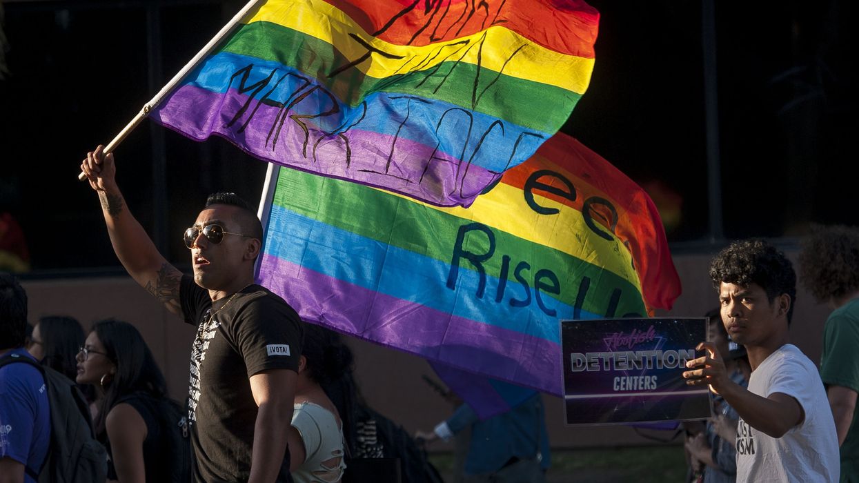 A person in a black shirt waves a Pride flag.