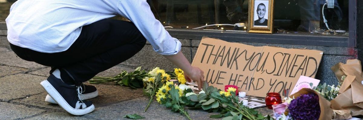 A person lights a candle at a memorial to Sinead O'Connor.