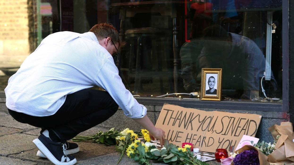 A person lights a candle at a memorial to Sinead O'Connor.