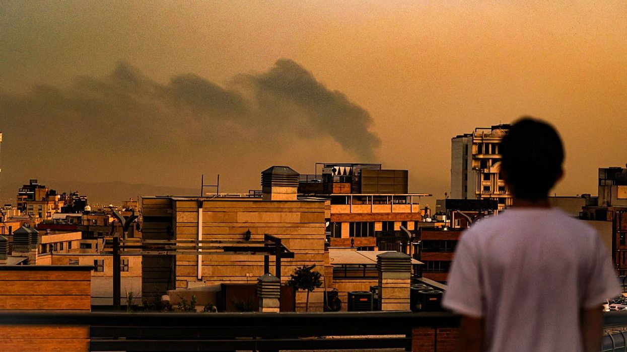 A person looks at Tehran's smoke-filled skyline following Israeli bombing.