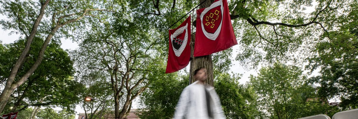 a person not in focus walks in front of two flags