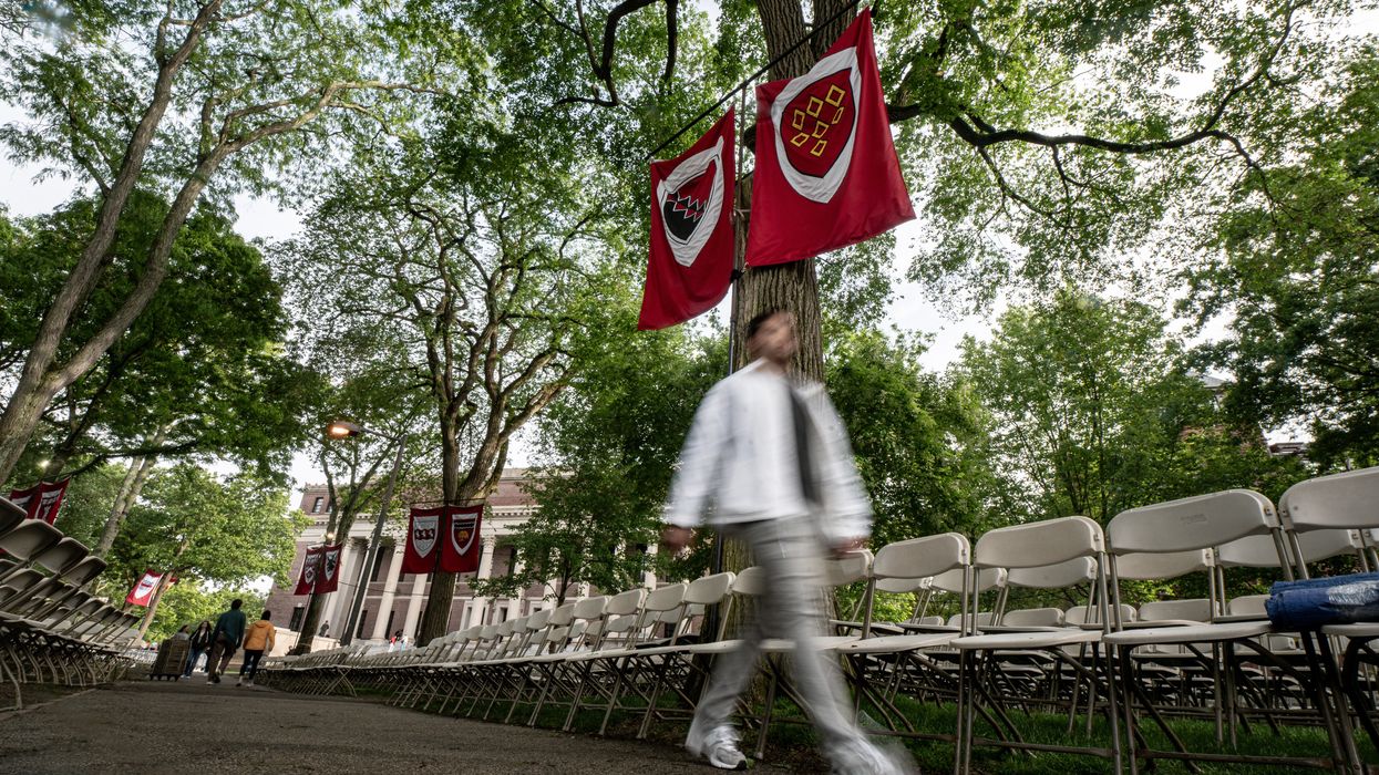 a person not in focus walks in front of two flags