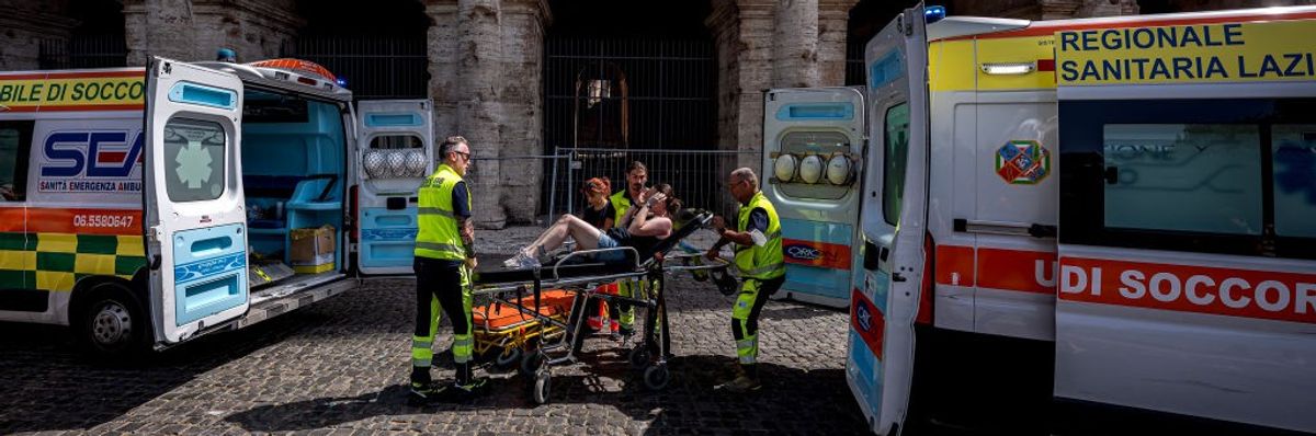 A person on a stretcher between two ambulances during a heatwave.
