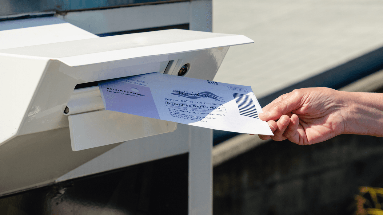a person places a ballot in a madilbox