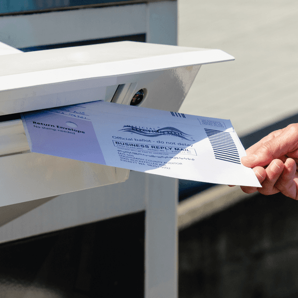 a person places a ballot in a madilbox