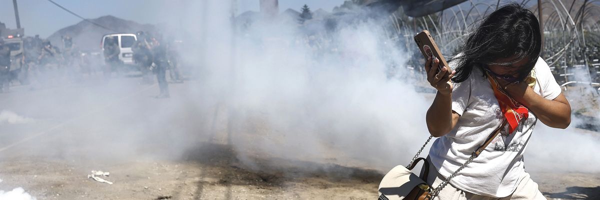 A person reacts to a smoke canister deployed by federal agents blocking protestors