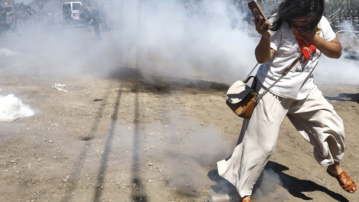 A person reacts to a smoke canister deployed by federal agents blocking protestors