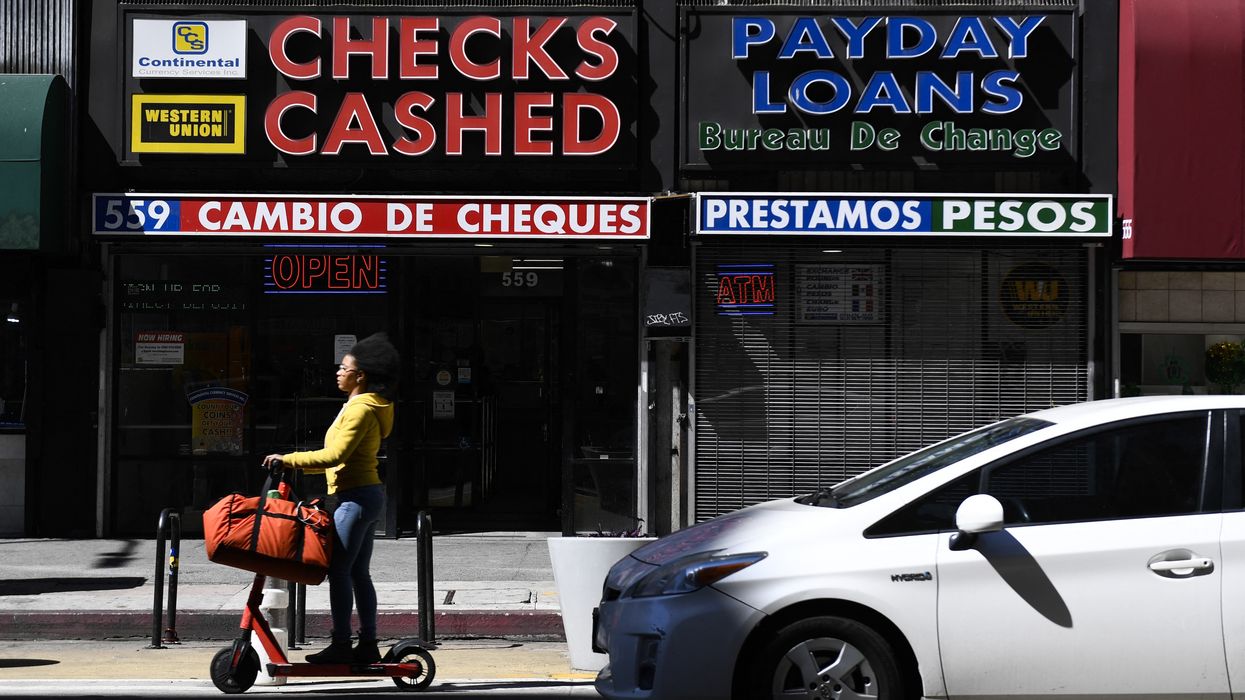 A person rides a scooter past a check cashing and payday loans store on March 11, 2022 in downtown Los Angeles, California.