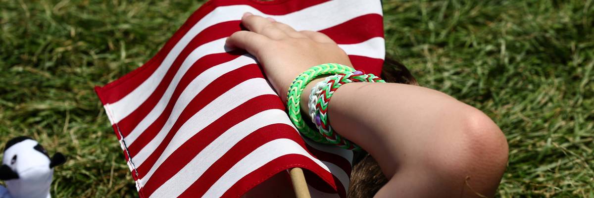 A person shields themself from the heat with a US flag.