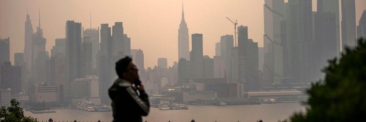 A person stares at a smoky New York City skyline.