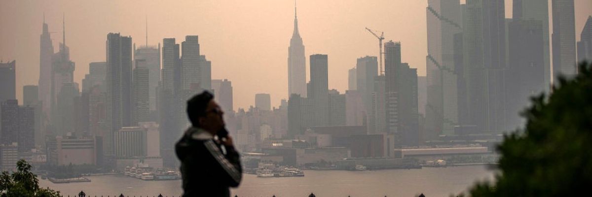 A person stares at a smoky New York City skyline. 