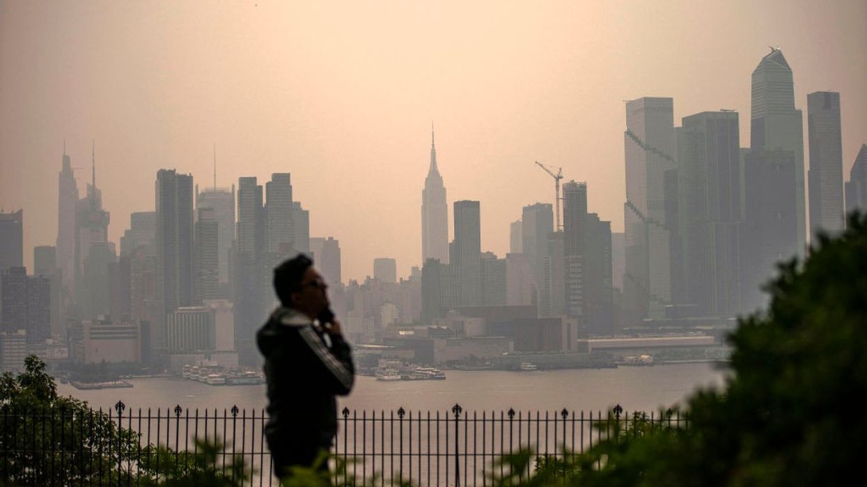 A person stares at a smoky New York City skyline.