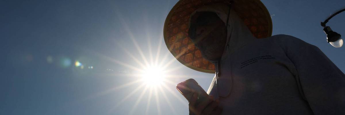 A person wears a hat for shade under the morning sun
