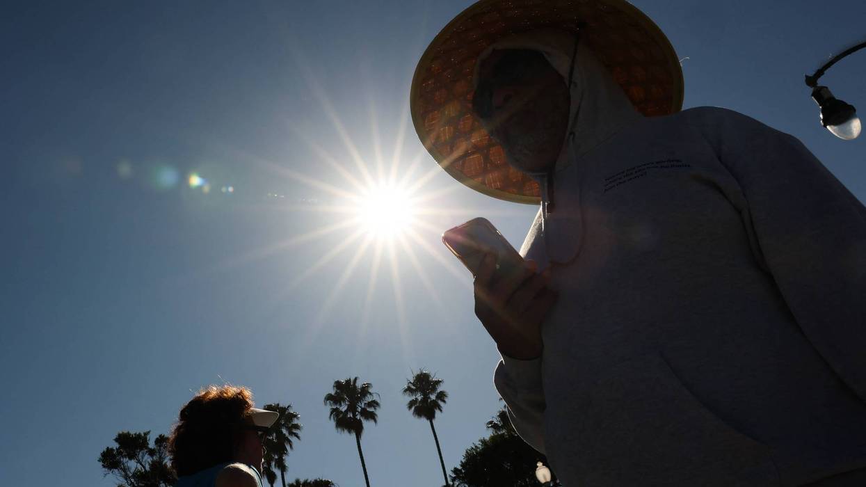 A person wears a hat for shade under the morning sun