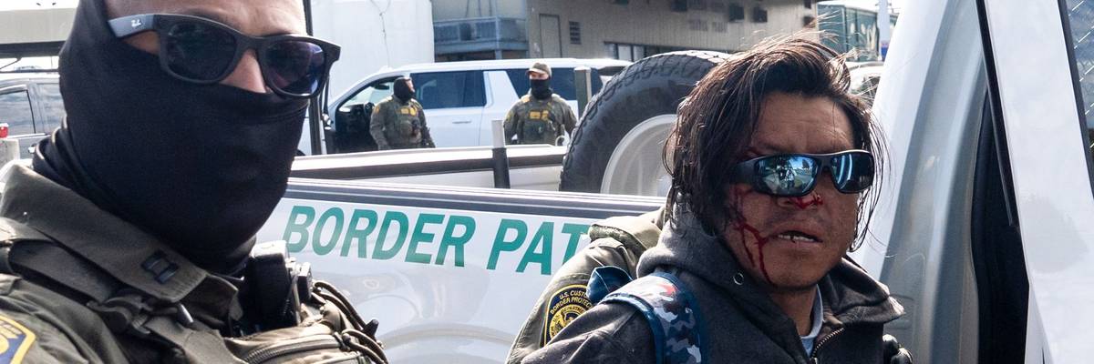 A person with a bloody face is arrested by a federal agent