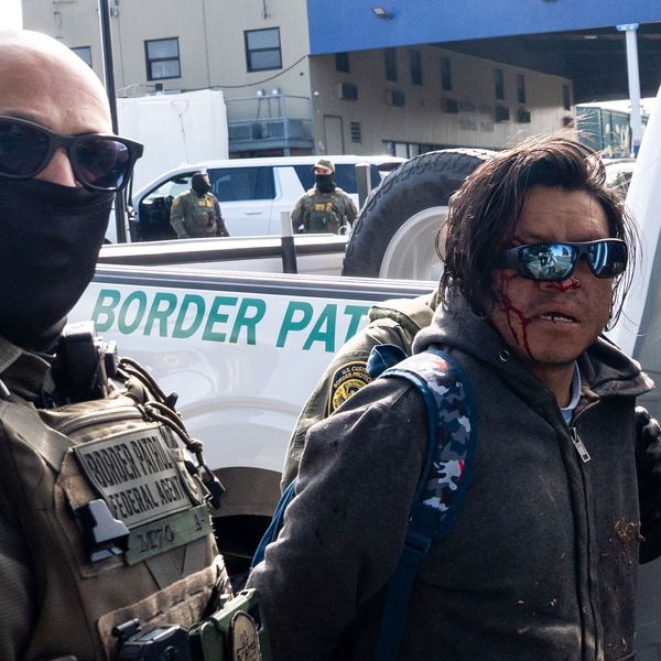 A person with a bloody face is arrested by a federal agent