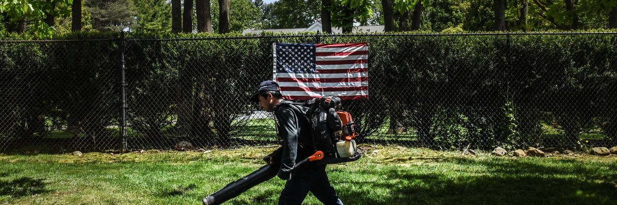 A person working as a leaf blower walks past an American flag on May 27, 2020 in Old Westbury, New York. (Photo by Stephanie Keith/Getty Images)