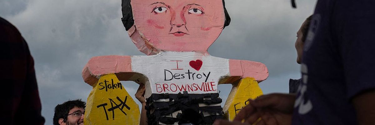 A piñata of Elon Musk wearing a shirt saying, "I love destroy Brownsville" and holding money bags.