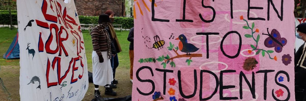 A pink sign reading, "Listen to students. #EndFossil."