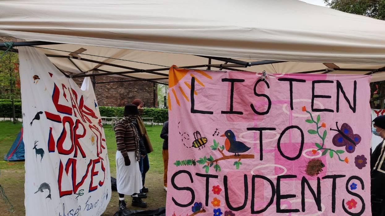 A pink sign reading, "Listen to students. #EndFossil."