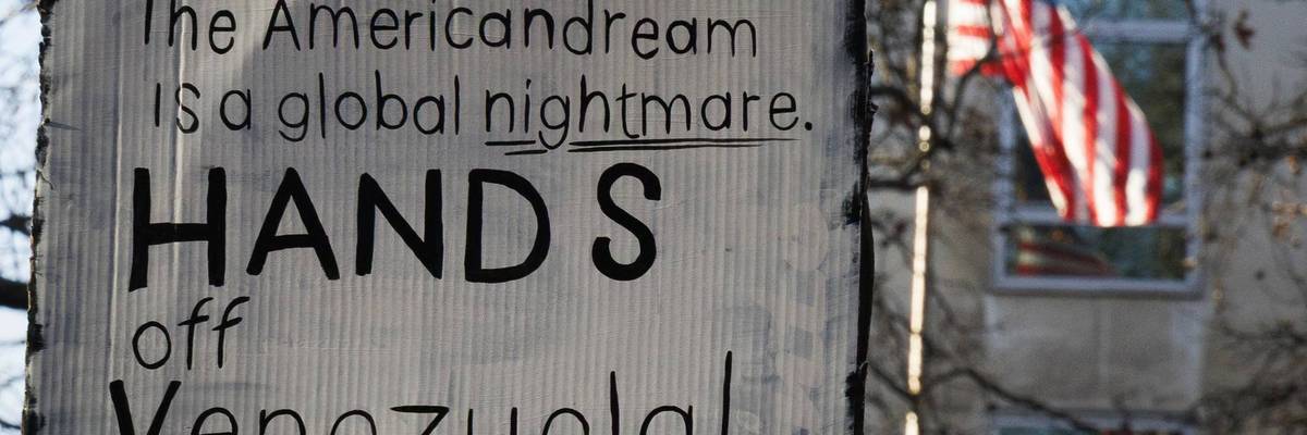 A placard reads, "American dream is a global nightmare, hands off Venezuela."