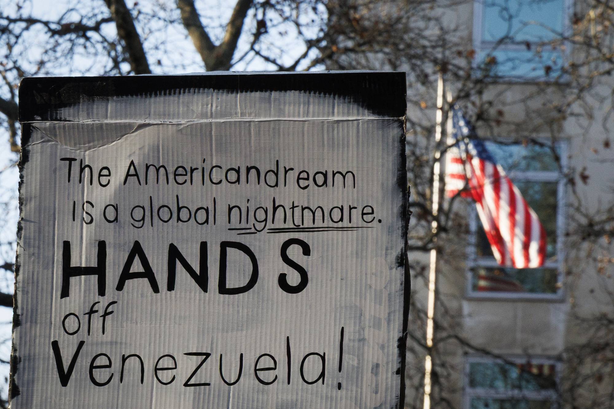 A placard reads, "American dream is a global nightmare, hands off Venezuela."