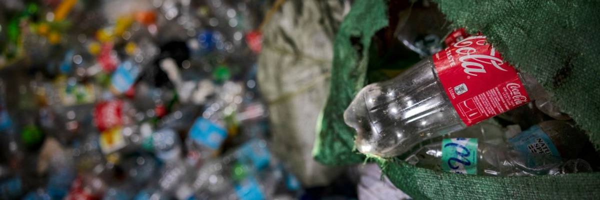 A plastic Coca-Cola bottle being tossed into a dump.