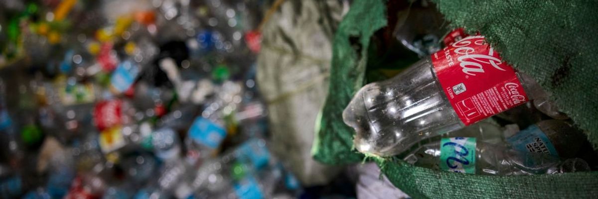 A plastic Coca-Cola bottle being tossed into a dump.
