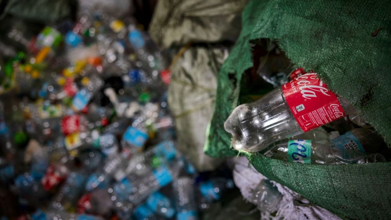 A plastic Coca-Cola bottle being tossed into a dump.