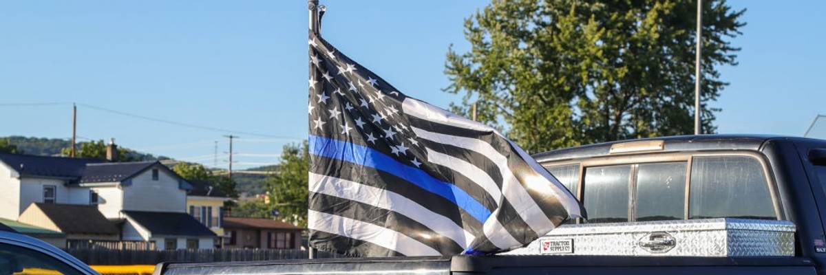 A police flag flies from a pickup truck.