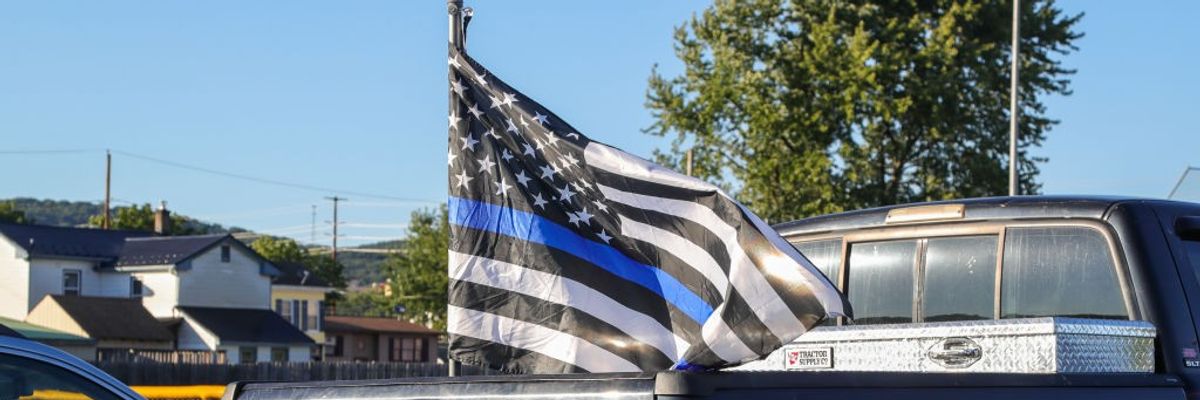 A police flag flies from a pickup truck.