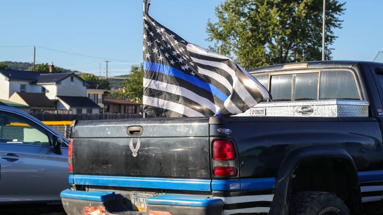 A police flag flies from a pickup truck.