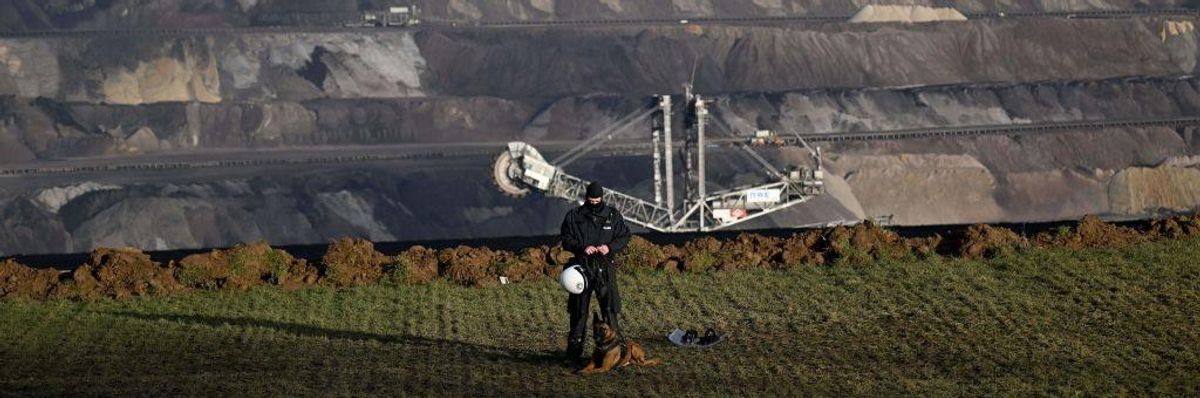 A policeman with a dog stands on the edge of a lignite mine in the village of Luetzerath, western Germany