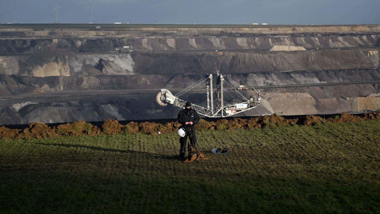 A policeman with a dog stands on the edge of a lignite mine in the village of Luetzerath, western Germany