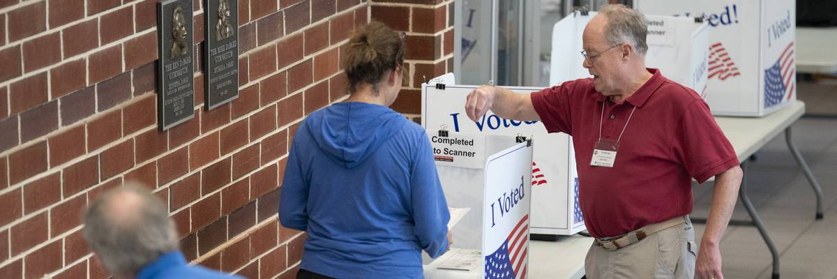 A poll worker helps a woman cast a midterm primary vote on Election Day