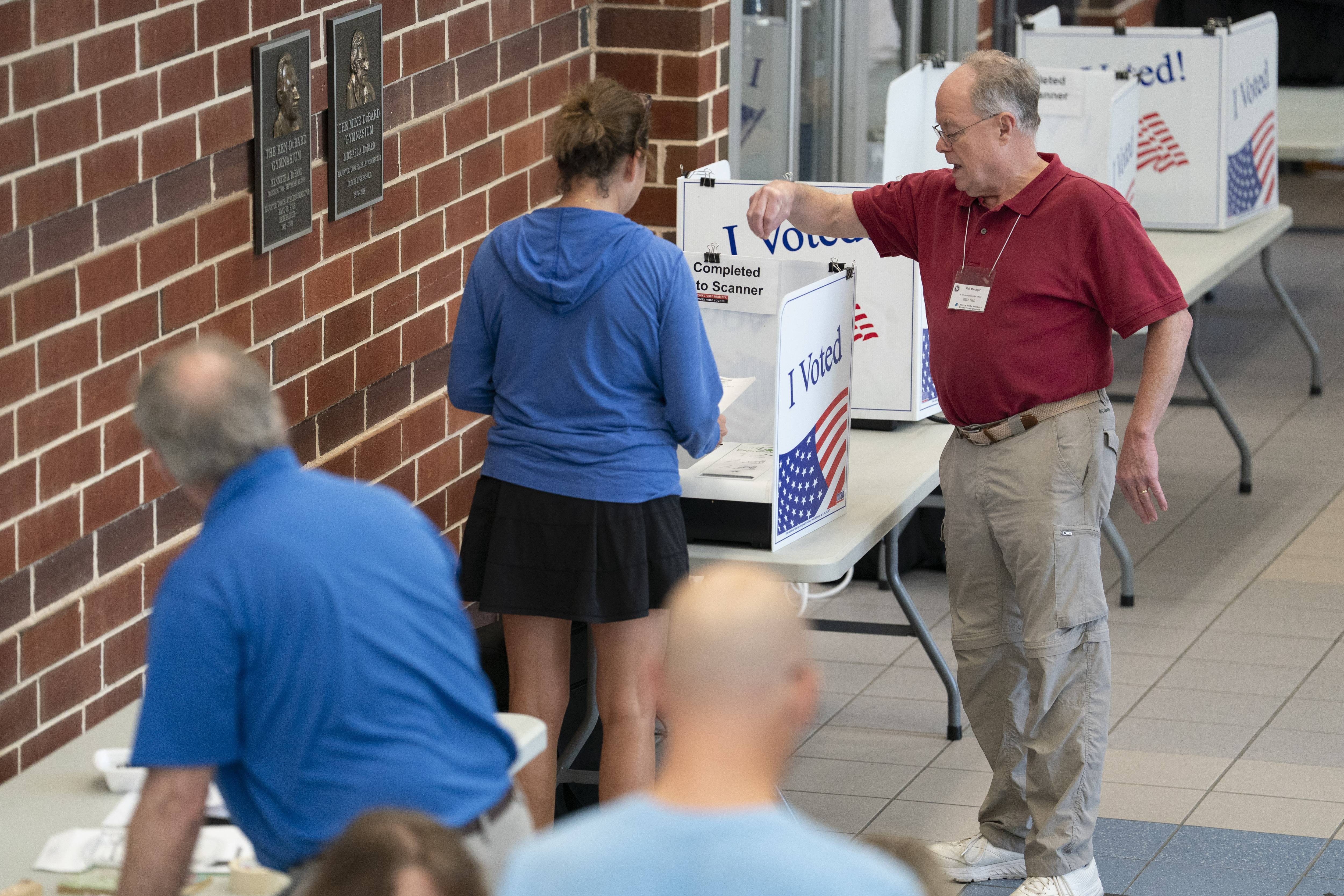 A poll worker helps a woman cast a midterm primary vote on Election Day