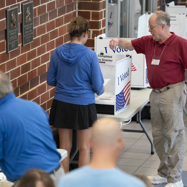 A poll worker helps a woman cast a midterm primary vote on Election Day